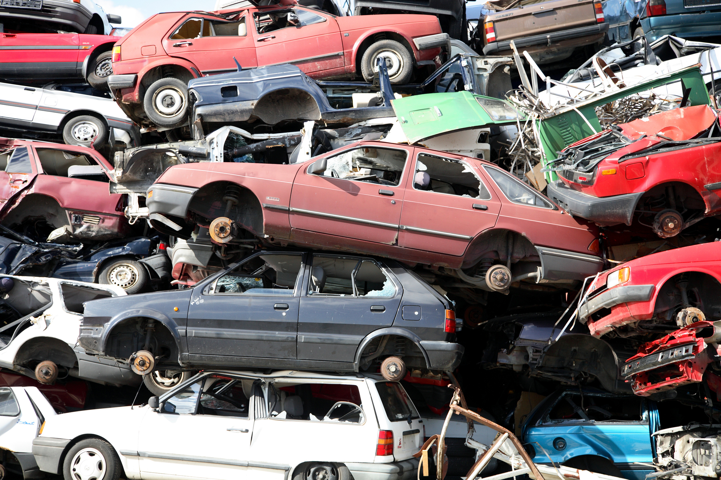 A large pile of abandoned scrap cars in an open lot
